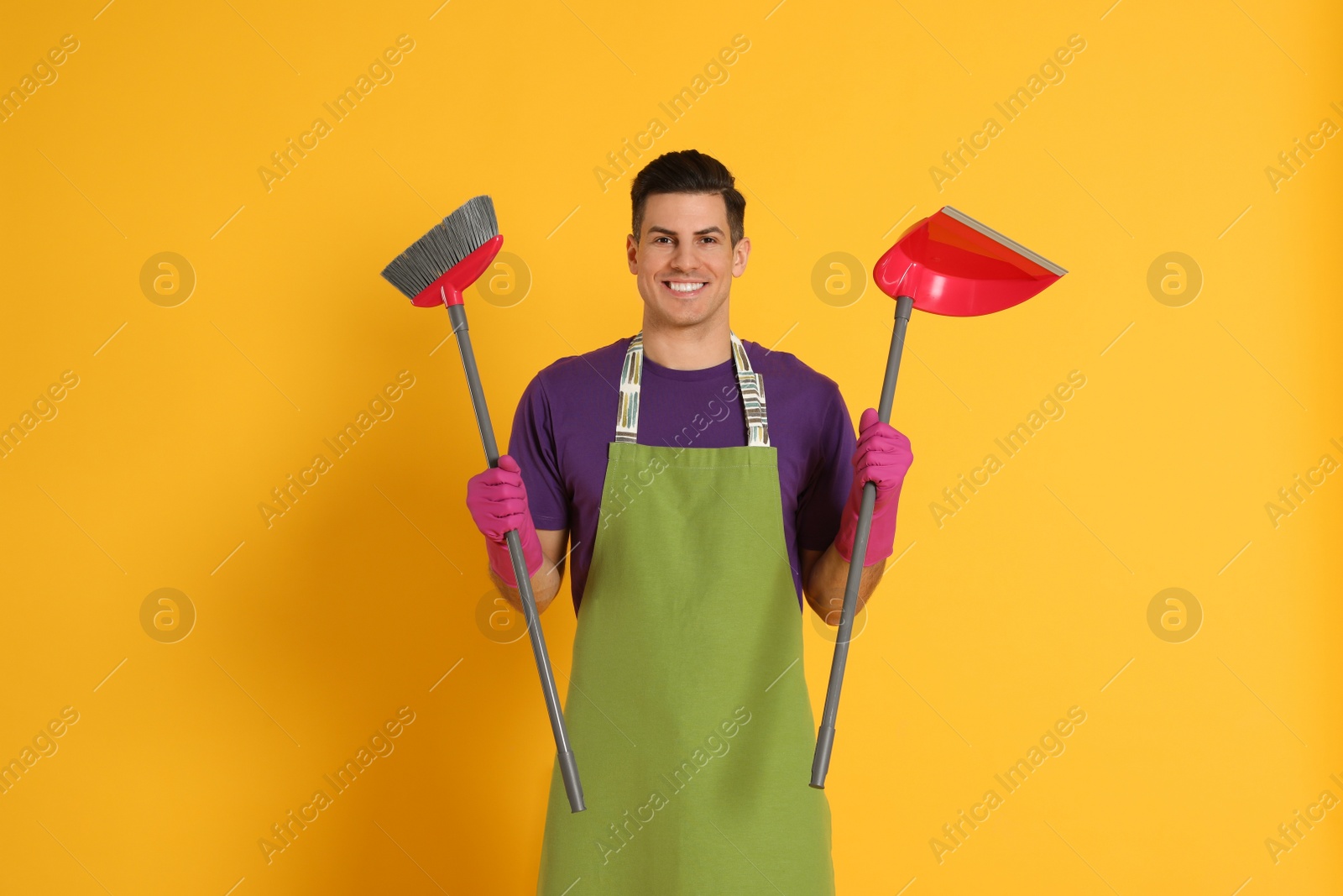 Photo of Man with broom and dustpan on orange background