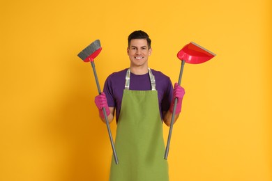 Man with broom and dustpan on orange background