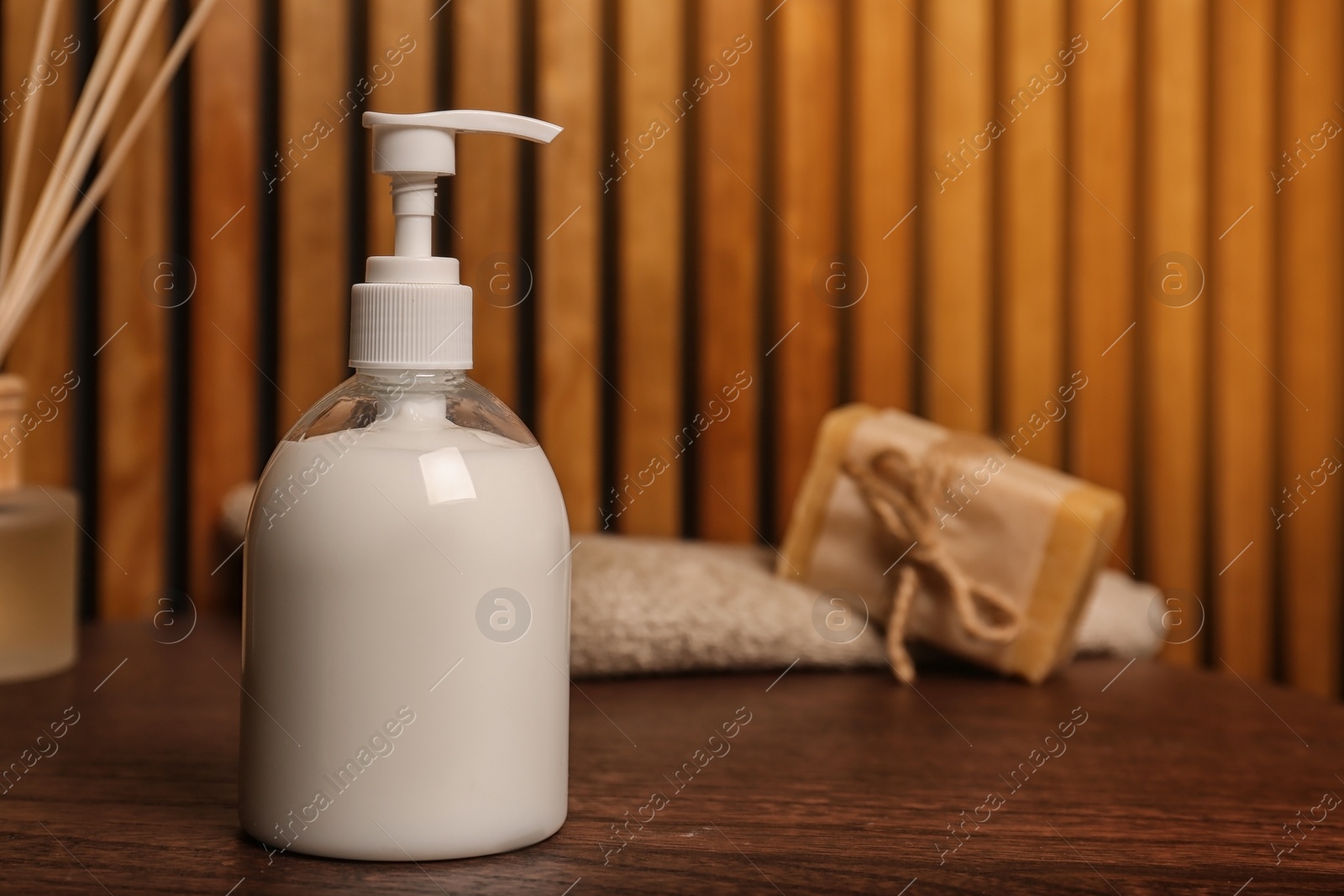 Photo of Bottle with liquid soap on table against blurred background. Space for text