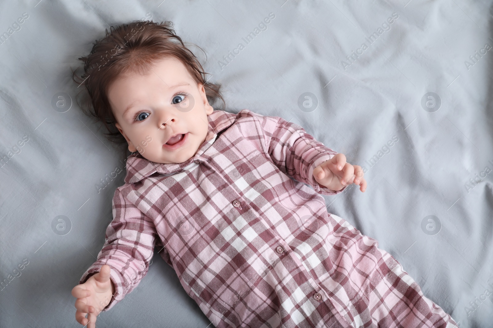 Photo of Cute little baby on bed, top view. Space for text