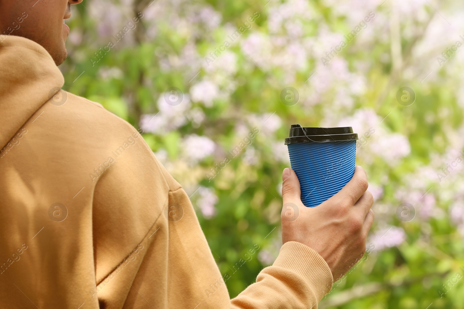 Photo of Man with takeaway coffee cup in park, closeup