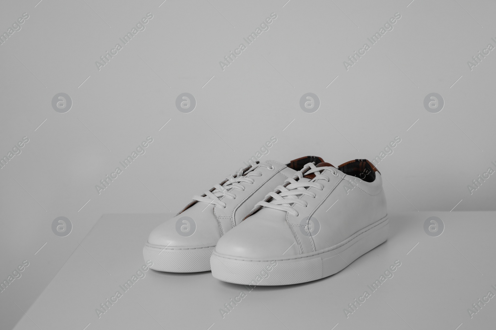 Photo of Pair of stylish sneakers on white table against light background. Space for text