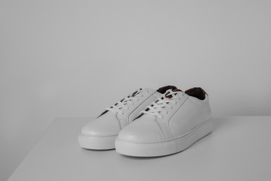Photo of Pair of stylish sneakers on white table against light background. Space for text