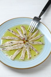 Tasty pickled anchovies with spices on white wooden table, above view