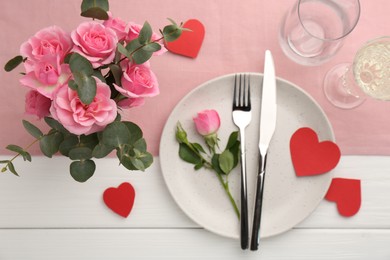 Photo of Romantic place setting with flowers and red paper hearts on white wooden table, flat lay. St. Valentine's day dinner