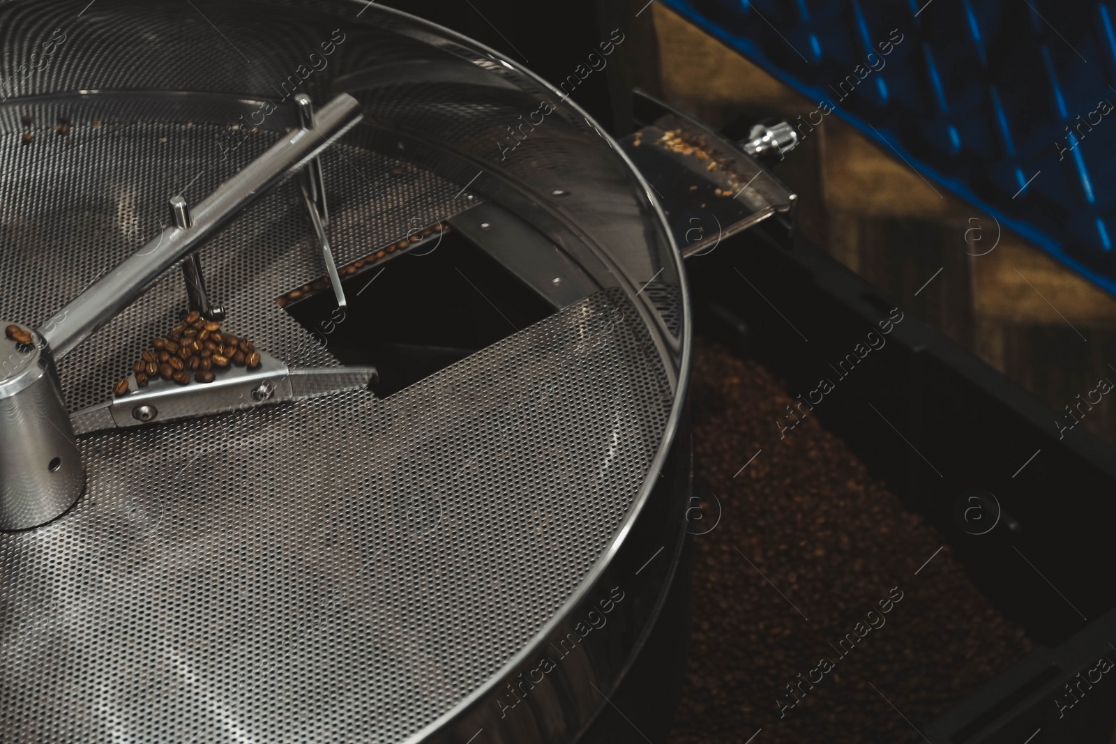 Photo of Modern coffee roaster machine with beans indoors, closeup