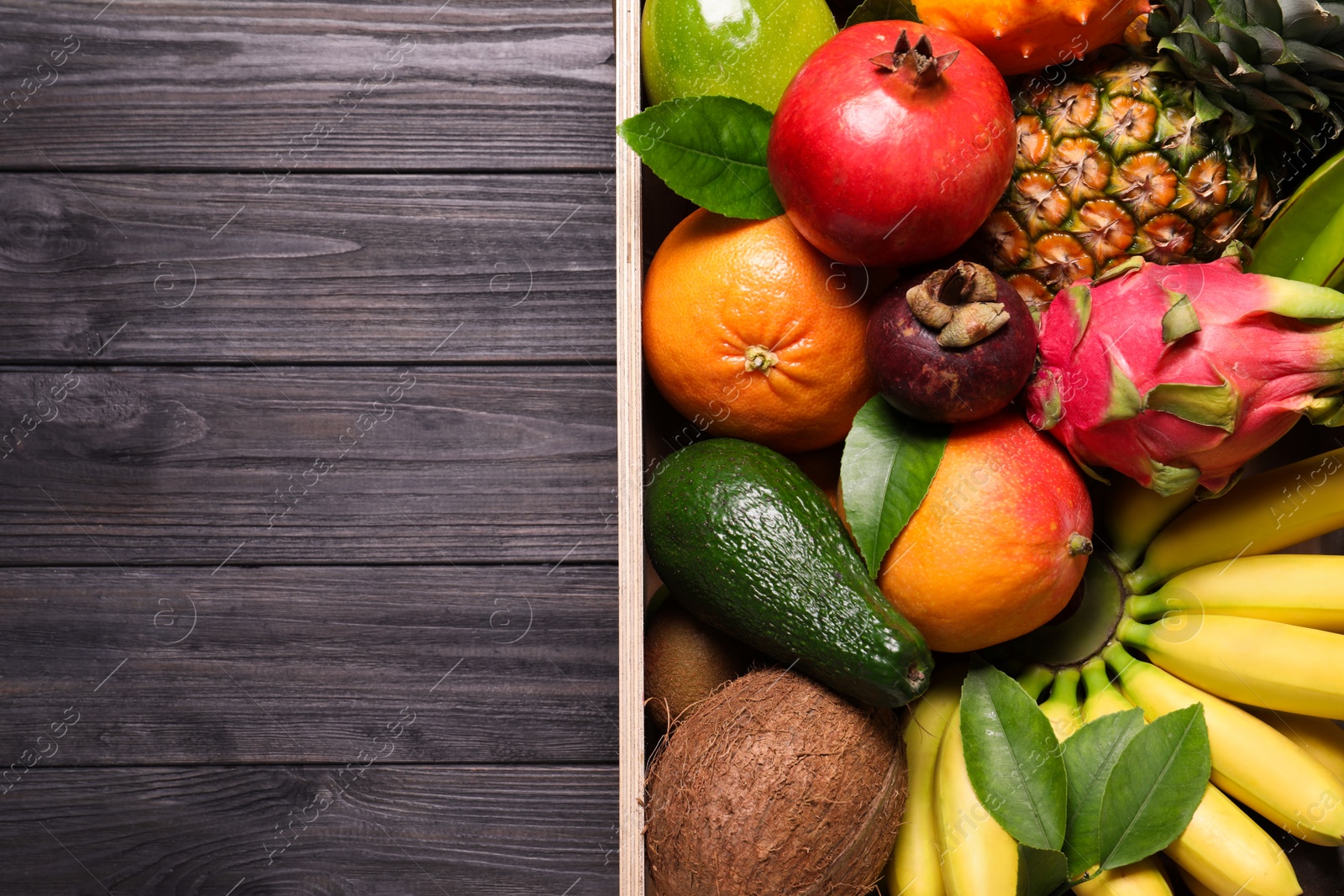 Photo of Crate with different exotic fruits on black wooden table, top view. Space for text