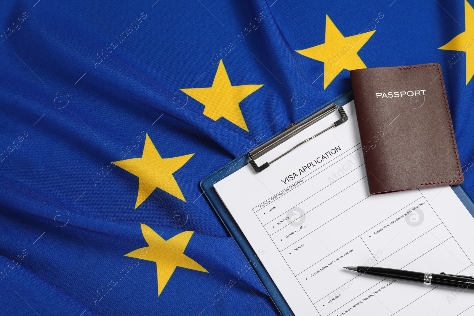 Photo of Visa application form, passport and pen on flag of European Union, flat lay. Space for text