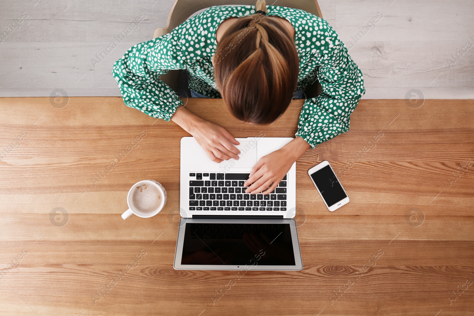 Photo of Woman working with laptop at table indoors, top view