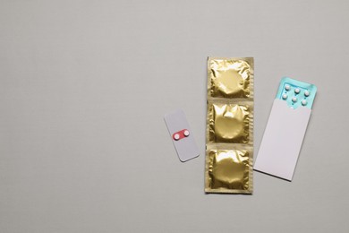 Photo of Contraception choice. Pills and condoms on light grey background, flat lay. Space for text