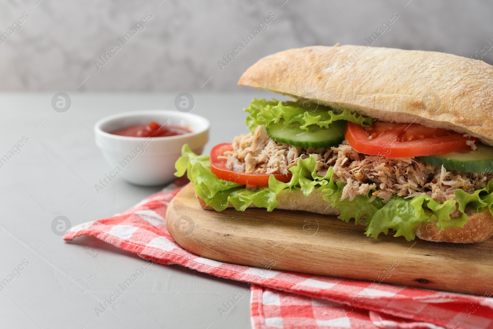 Photo of Delicious sandwich with tuna, vegetables and tomato sauce on light grey table, closeup. Space for text