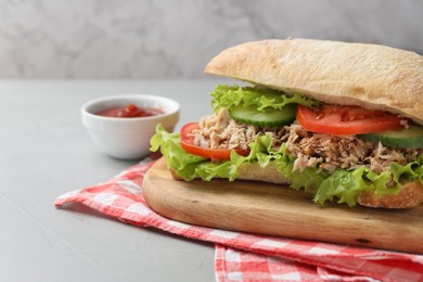 Delicious sandwich with tuna, vegetables and tomato sauce on light grey table, closeup. Space for text