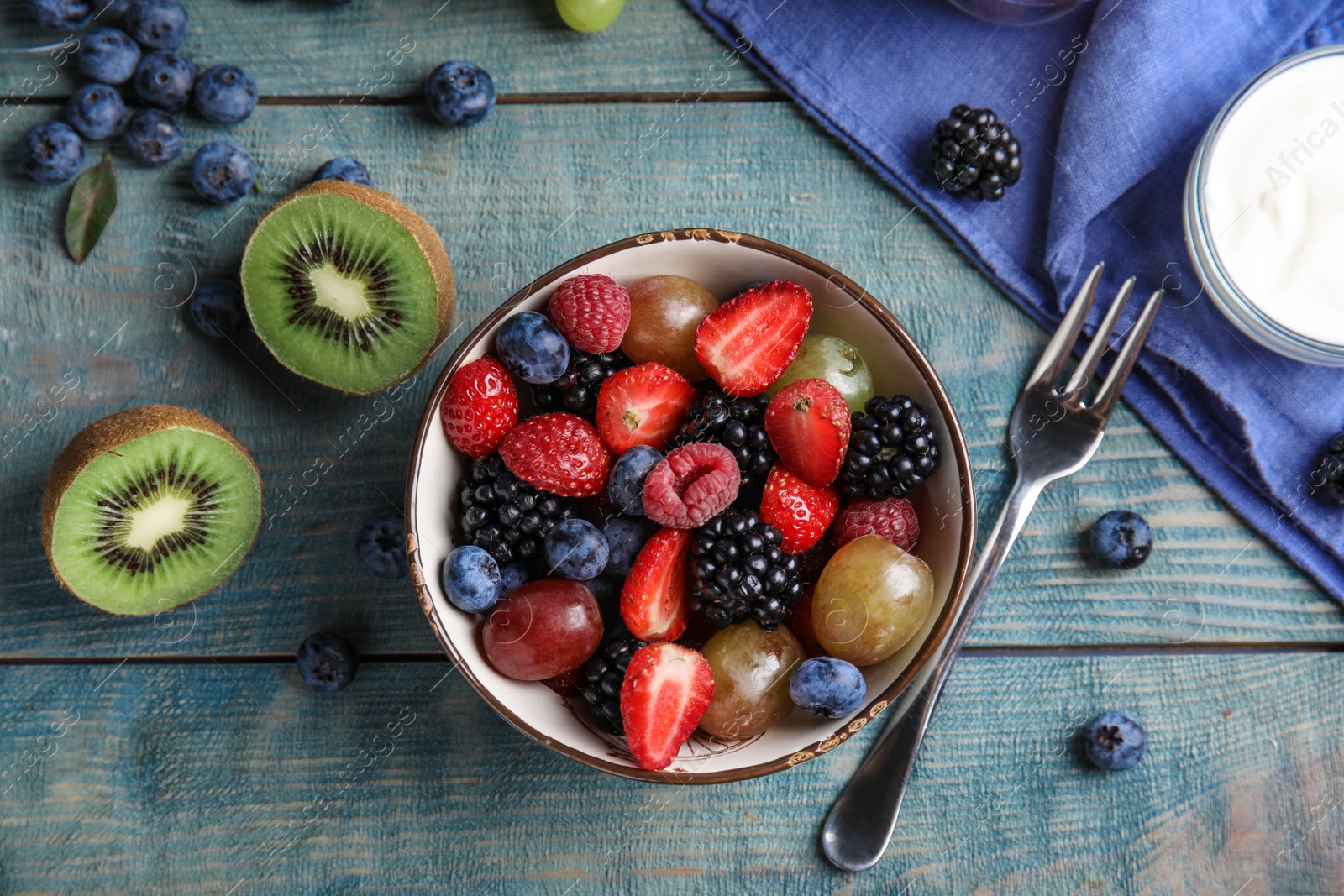 Photo of Fresh tasty fruit salad on blue wooden table, flat lay