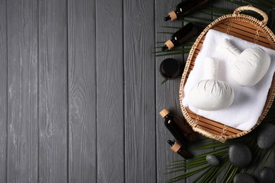 Photo of Flat lay composition with herbal massage bags and other spa products on grey wooden table, space for text