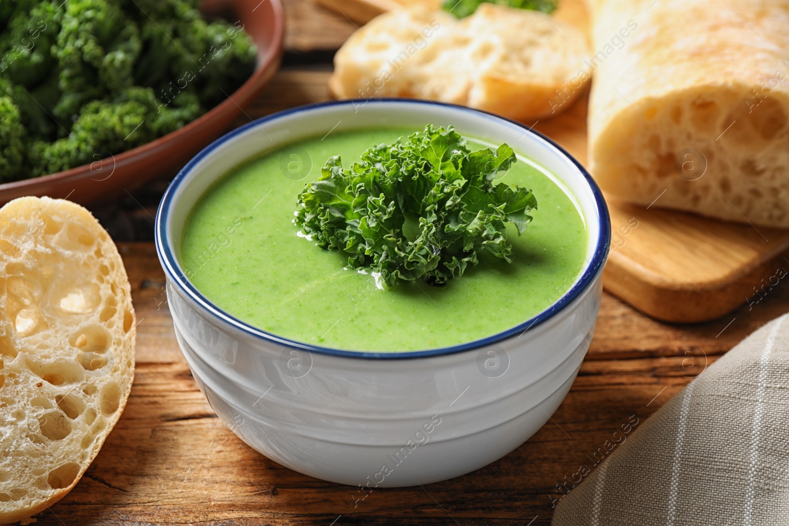 Photo of Tasty kale soup on wooden table, closeup