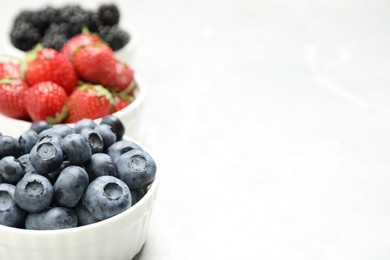 Photo of Different ripe berries on light table, closeup. Space for text