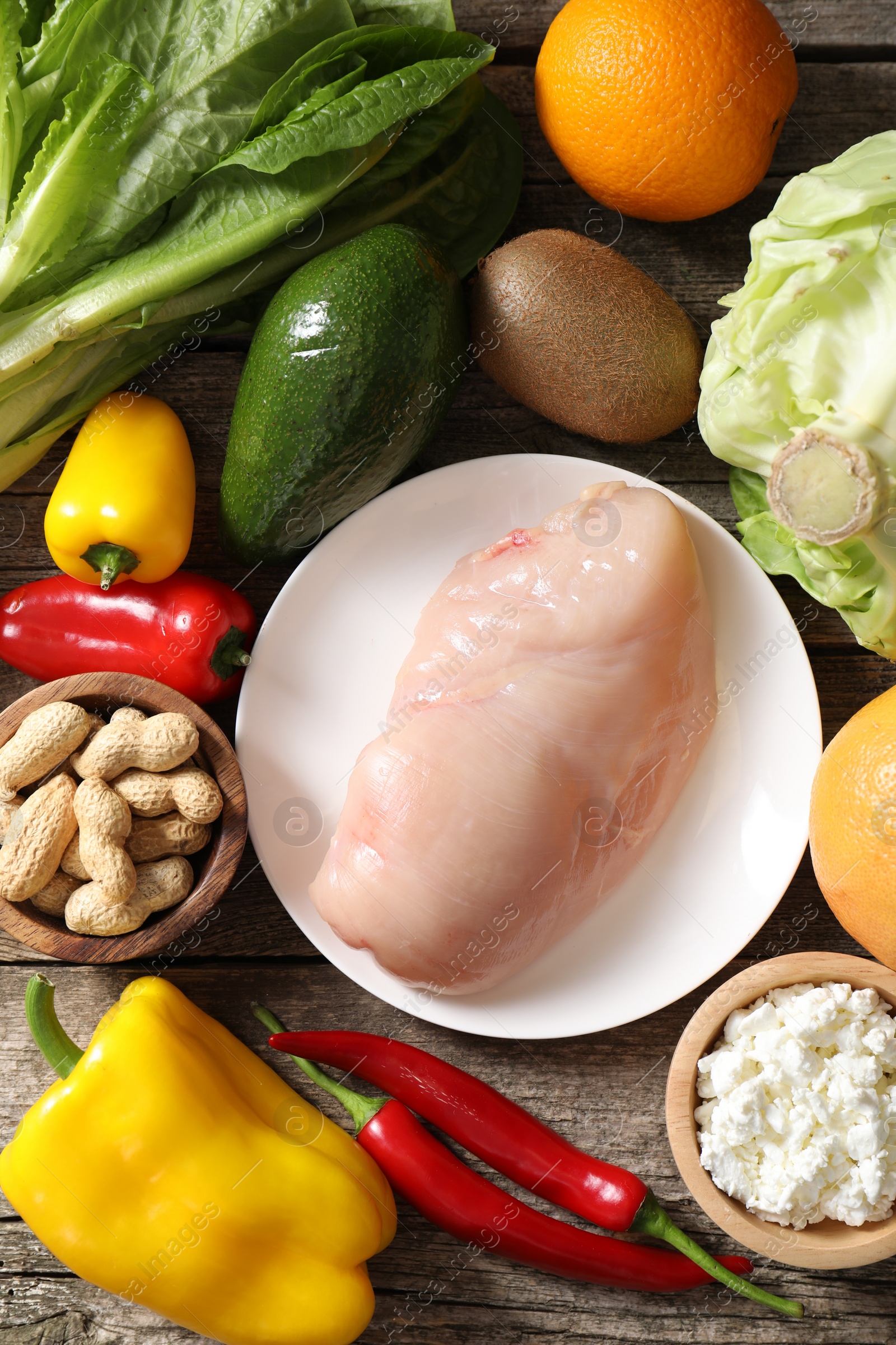 Photo of Healthy meal. Different vegetables and raw chicken breast on wooden table, flat lay