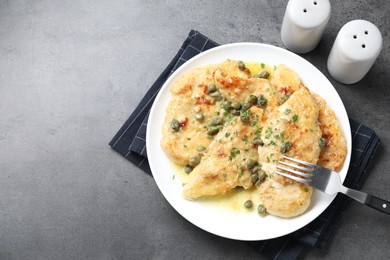 Photo of Delicious chicken piccata with herbs served on grey table, flat lay. Space for text