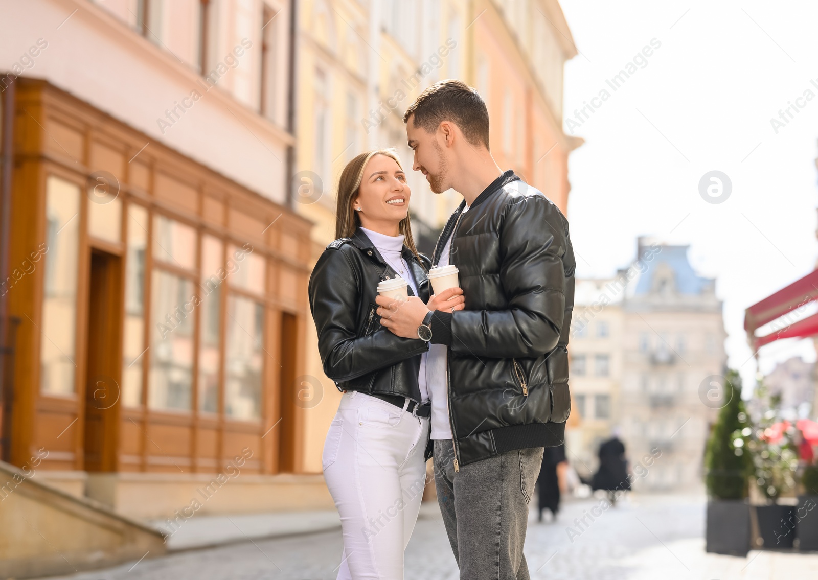 Photo of Lovely young couple with cups of coffee together on city street. Romantic date