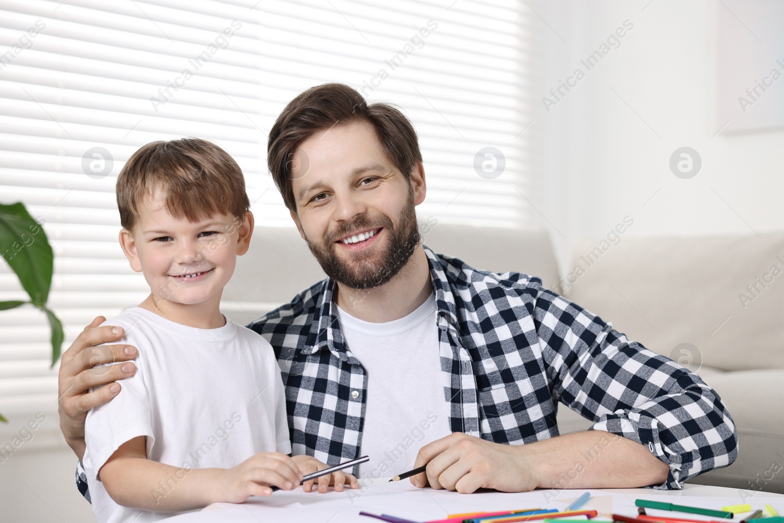 Photo of Family portrait of happy dad and son at table indoors