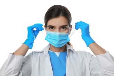 Photo of Doctor in medical gloves putting on protective mask against white background