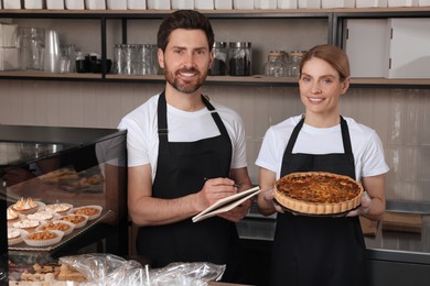 Photo of Sellers with notebook and freshly baked quiche in bakery shop
