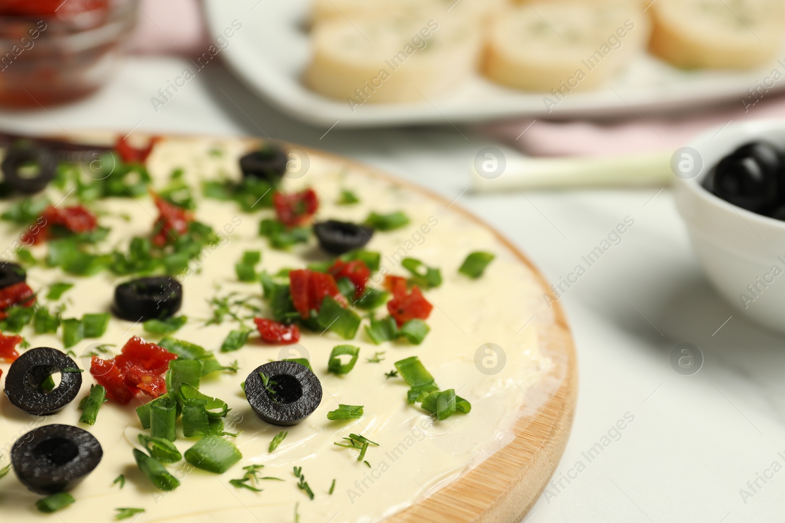 Photo of Fresh butter board with cut olives and onion on white table, closeup