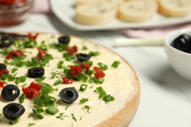 Photo of Fresh butter board with cut olives and onion on white table, closeup