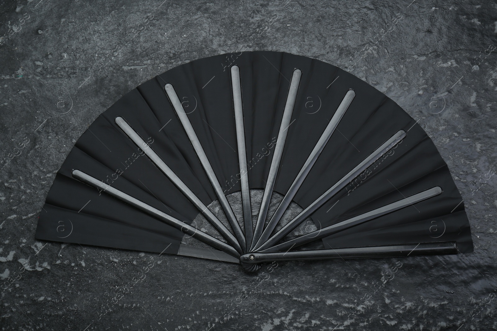 Photo of Stylish black hand fan on grey textured background, top view