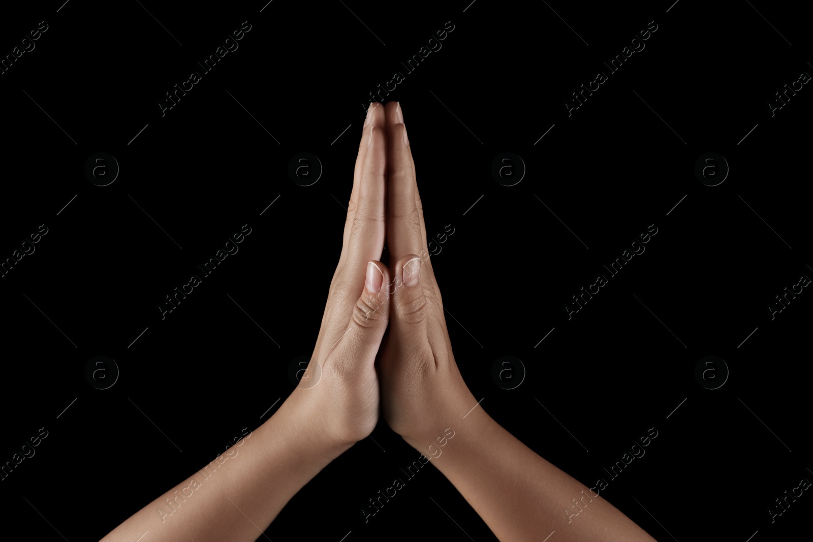 Photo of Woman holding hands clasped while praying on black background, closeup