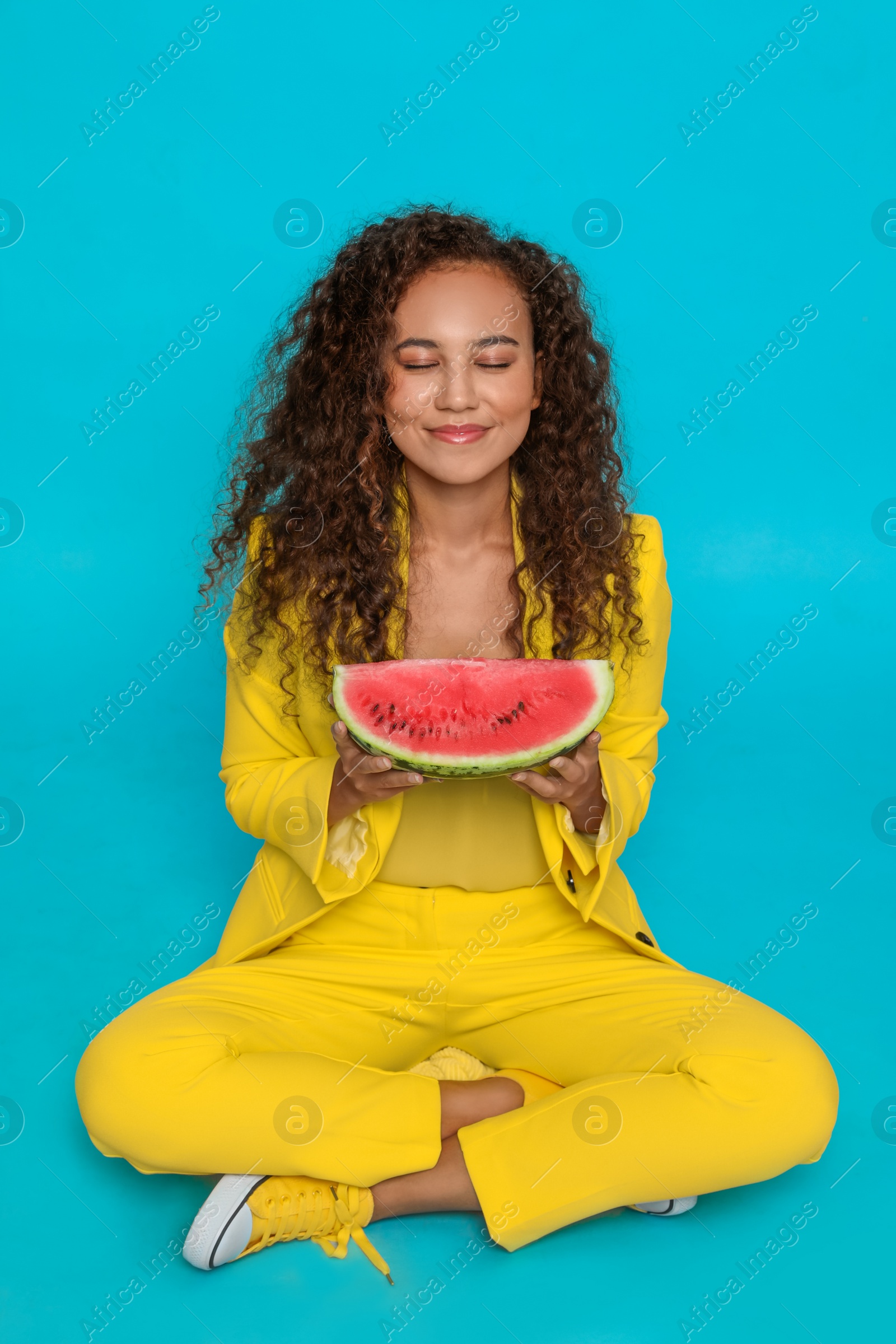 Photo of Beautiful young African American woman with watermelon on light blue background