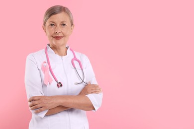 Photo of Doctor with pink ribbon and stethoscope on color background, space for text. Breast cancer awareness