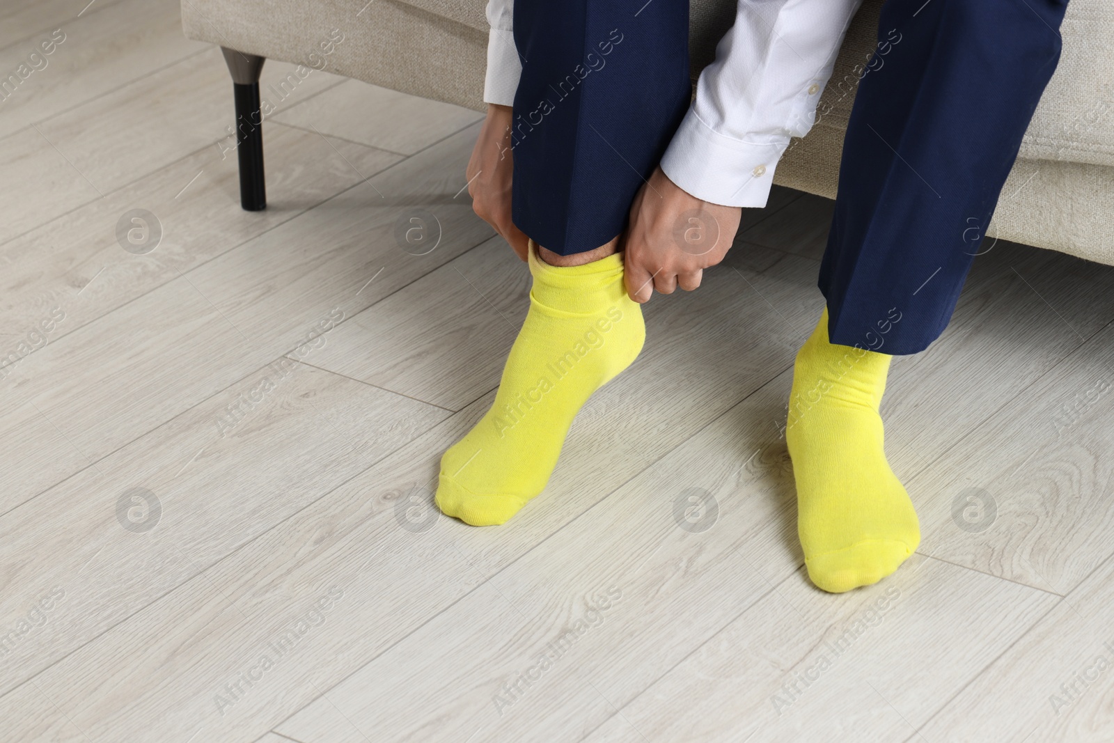 Photo of Man putting on yellow socks indoors, closeup