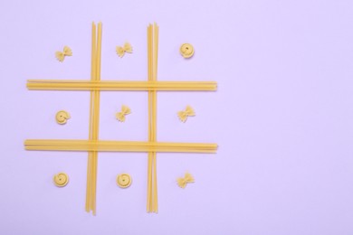 Tic tac toe game made with different types of pasta on lilac background, top view