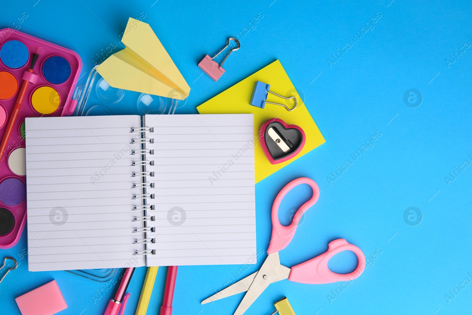 Photo of Flat lay composition with blank notebook and other school stationery on light blue background, space for text. Back to school