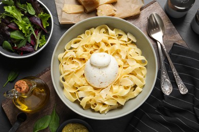 Photo of Delicious pasta with burrata cheese served on black table, flat lay