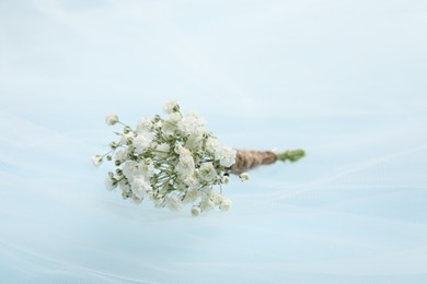 Photo of Wedding stuff. Stylish boutonniere and veil on light blue background, closeup