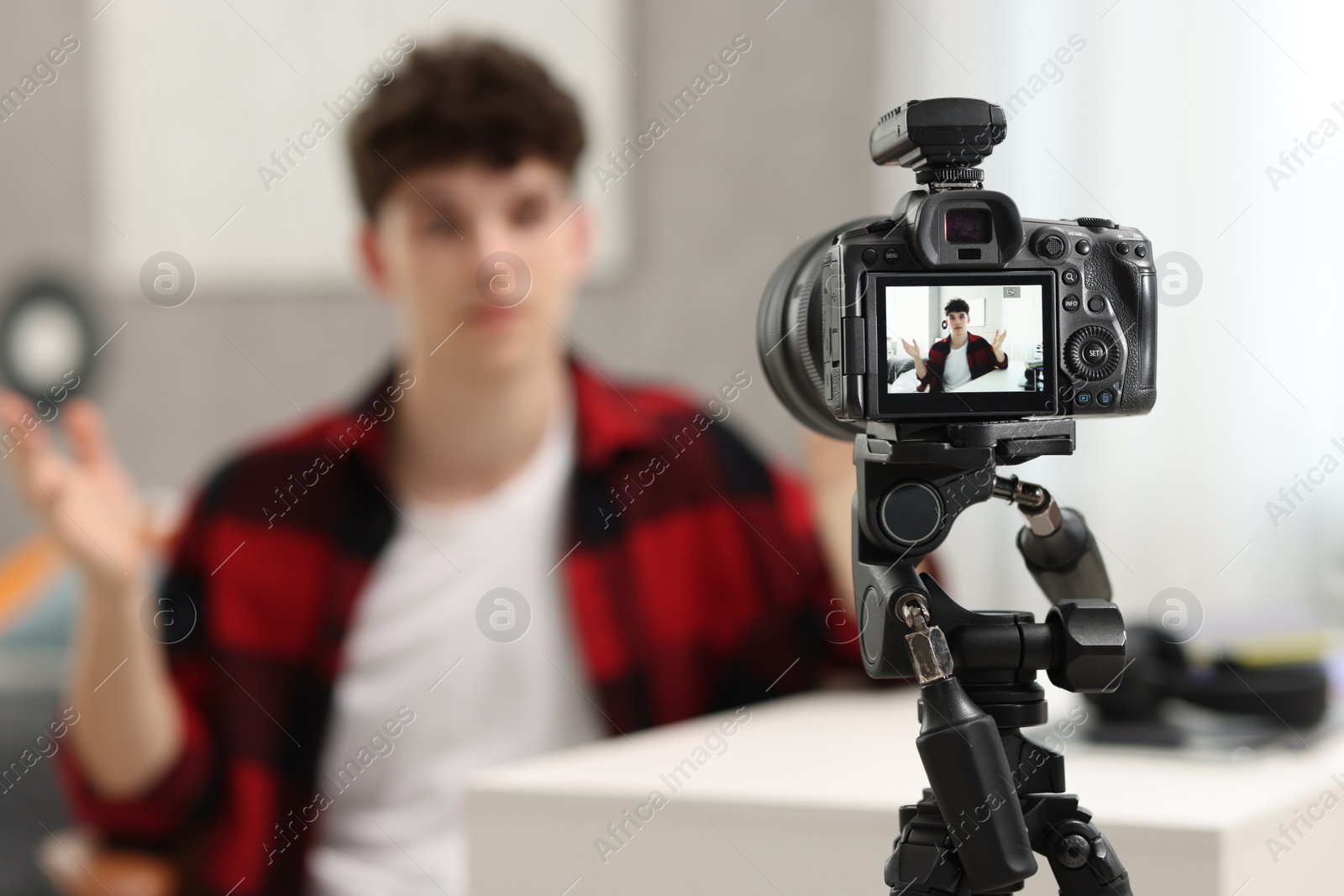 Photo of Teenage blogger explaining something while streaming at home, focus on camera