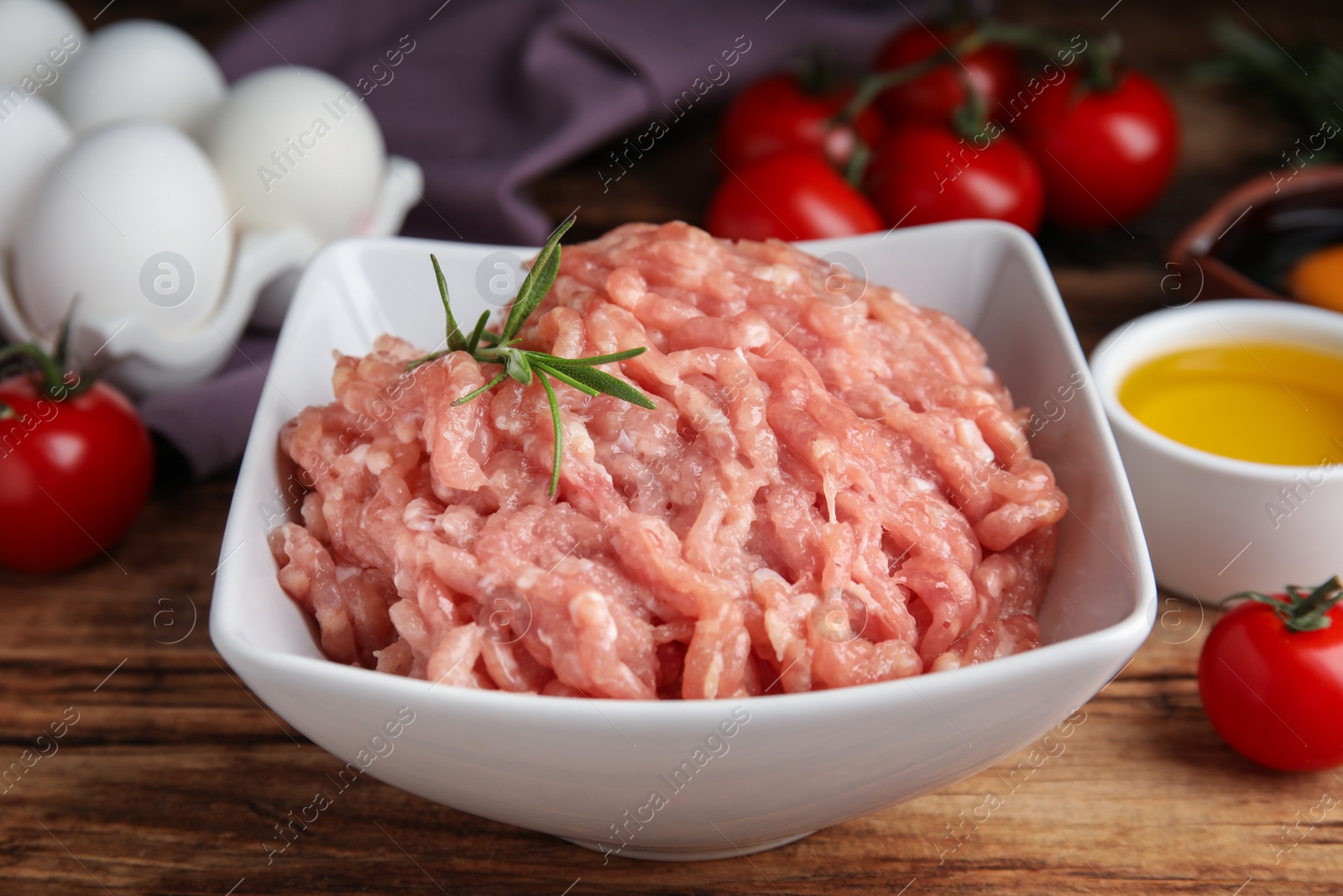 Photo of Raw chicken minced meat with rosemary on wooden table, closeup