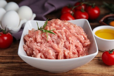 Raw chicken minced meat with rosemary on wooden table, closeup