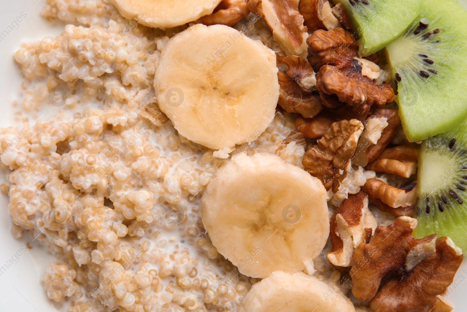 Photo of Quinoa porridge with walnuts, kiwi, banana and milk as background, top view