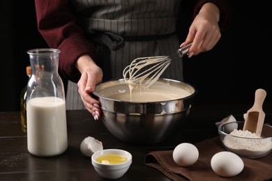 Photo of Woman making dough with whisk in bowl at table, closeup