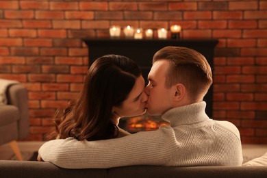 Photo of Lovely couple kissing near fireplace at home