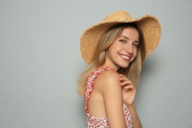 Beautiful young woman wearing straw hat on light grey background, space for text. Stylish headdress