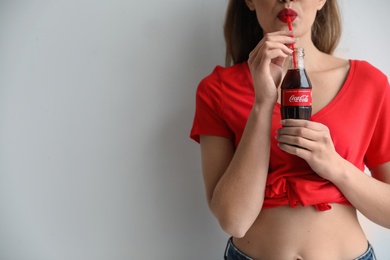 Photo of MYKOLAIV, UKRAINE - NOVEMBER 28, 2018: Young woman drinking Coca-cola on white background, closeup. Space for text