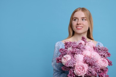 Beautiful woman with bouquet of spring flowers on light blue background, space for text