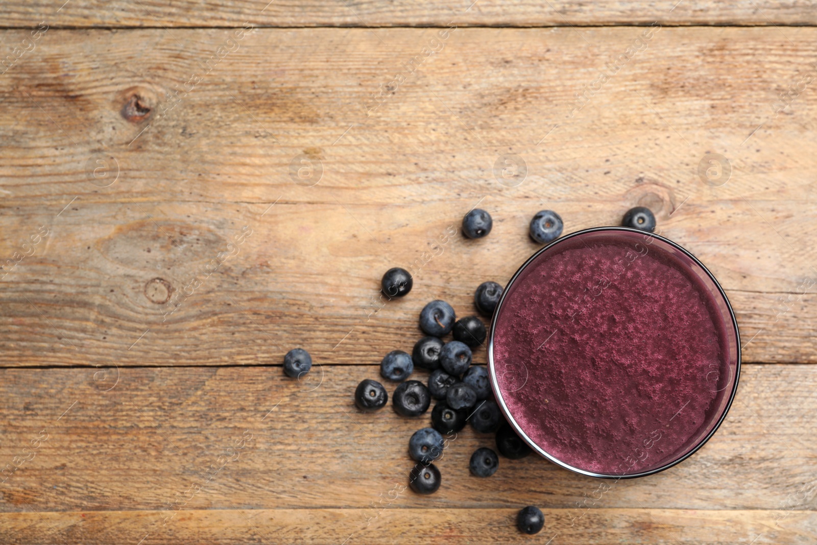 Photo of Fresh acai drink and berries on wooden table, flat lay. Space for text