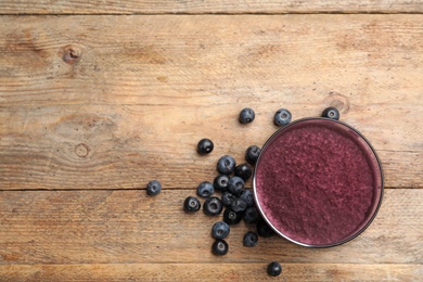 Fresh acai drink and berries on wooden table, flat lay. Space for text