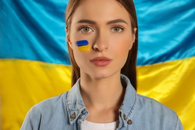 Photo of Young woman with face paint near Ukrainian flag