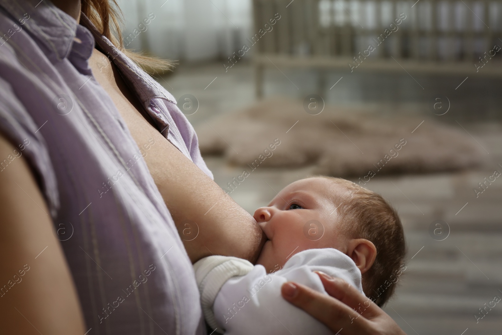 Photo of Young woman breast feeding her little baby at home, closeup